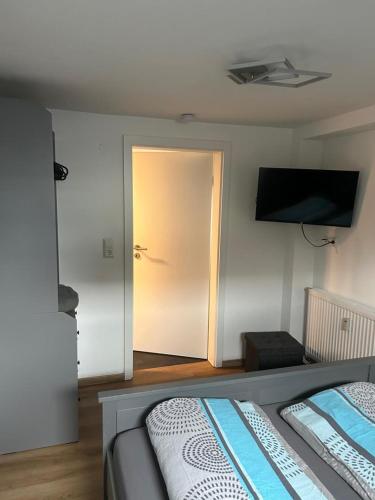 a bedroom with a bed and a door with a television at NEU! Moderne Ferienwohnung Knüllwald in Knüllwald