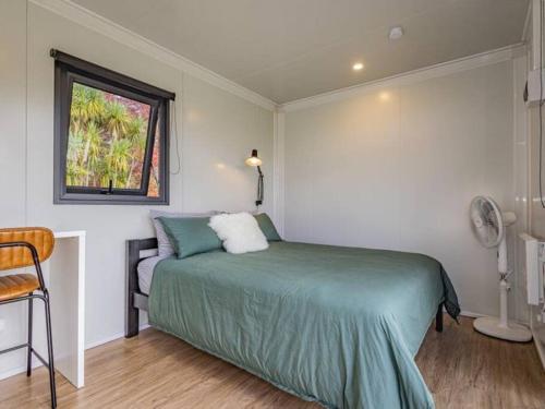 a bedroom with a green bed and a window at Rural retreat - Rua cabin in Ohakune