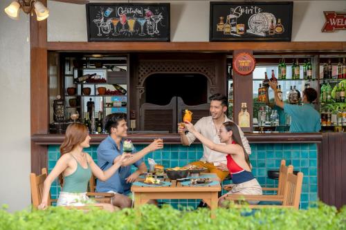 a group of people sitting at a bar at Grand Mercure Bangkok Atrium in Bangkok