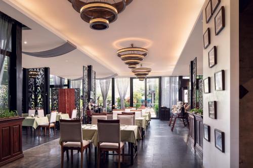 een restaurant met tafels en stoelen en grote ramen bij Lynnaya Urban River Resort in Siem Reap