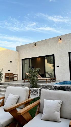 eine Terrasse mit zwei weißen Stühlen und einem Gebäude in der Unterkunft شاليهات بالما in Al Hofuf