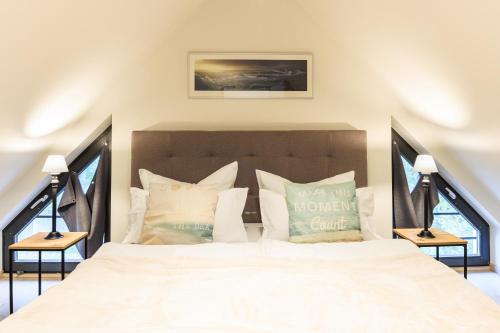 a bedroom with a large white bed with pillows at Goldregen - Domizil am Ostseewald in Zingst