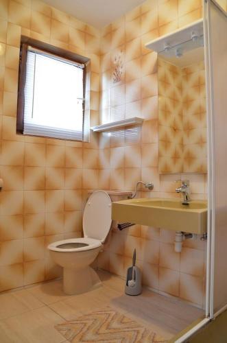 a bathroom with a toilet and a sink and a window at Apartments Ruza (obitelj Cerkez) in Supetarska Draga