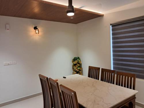 a dining room with a marble table and chairs at Seashells Pentagon Calicutbeach in Kozhikode