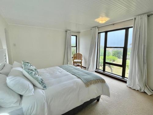 a bedroom with a white bed and a large window at Ocean Mooring Beach Villa Sea View in Port Alfred