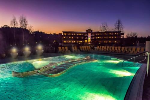 a swimming pool at night with a building in the background at Thermenhotel PuchasPLUS Stegersbach in Stegersbach