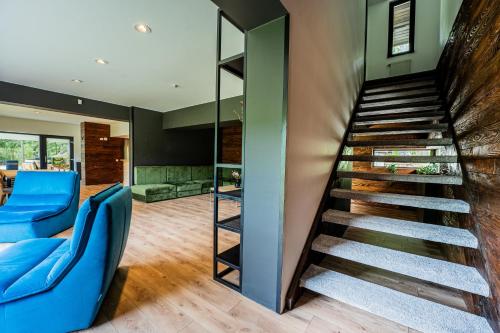 a staircase in a living room with blue chairs at Cabana Haiducului in Teşila