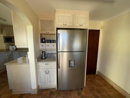 a stainless steel refrigerator in a kitchen with white cabinets at Ocean Mooring Beach Villa Sea View in Port Alfred