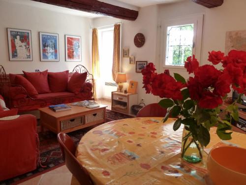 un salon avec une table et un vase de fleurs rouges dans l'établissement La Calvinette, à Pernes-les-Fontaines