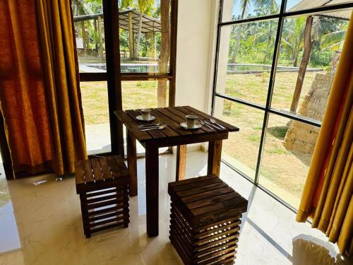 a wooden table in front of a large window at A4 Villa Safari Cottage in Udawalawe