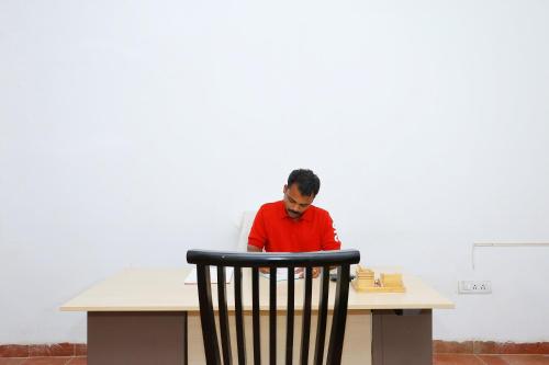 a man sitting at a table with a chair at Super Townhouse Island Inn in Cochin
