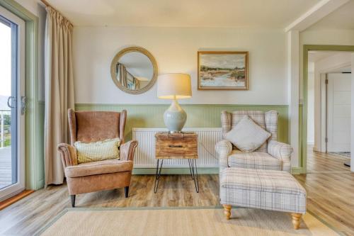 a living room with two chairs and a table with a lamp at New Build Lodge With Stunning Views of Loch Awe in Hayfield