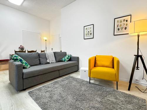 a living room with a gray couch and a yellow chair at 2 Zimmer Apartment für 6 P, 15 min zum Flughafen in Sirnau