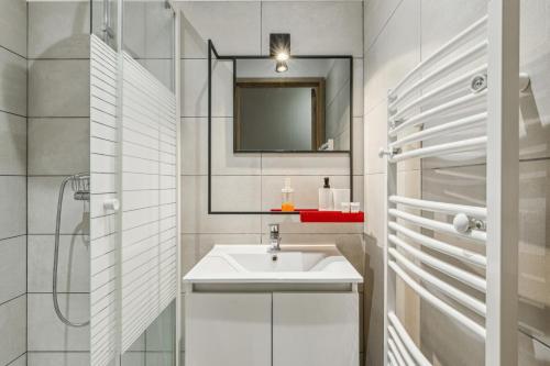 une salle de bain blanche avec un lavabo et un miroir dans l'établissement Lavie Maison large comfy flat, à Bordeaux