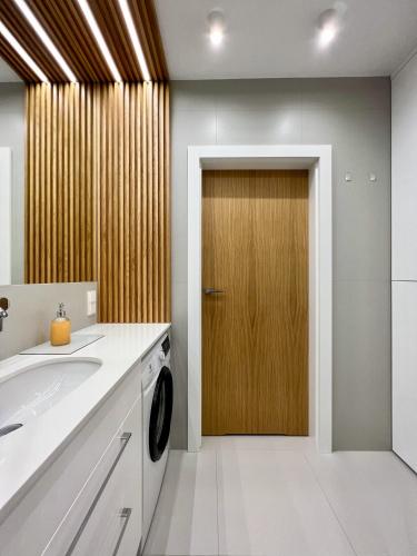a bathroom with a sink and a wooden door at SuperApart Sternicza apt 43 in Warsaw
