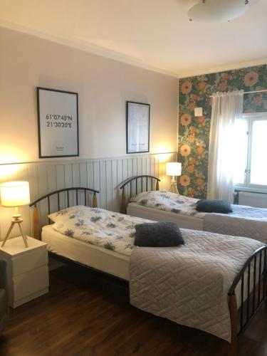 two beds in a hotel room with two lamps at Haus Anna in Rauma