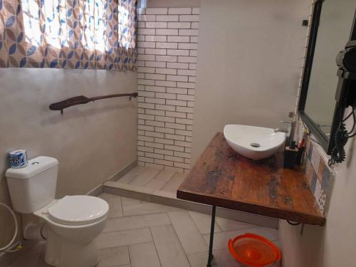 a bathroom with a toilet and a sink on a wooden table at Boulevard Inn Mt Meru in Arusha