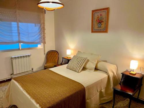 Un dormitorio con una cama y dos lámparas y una ventana. en Adela, en Marín