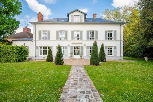 Une grande maison blanche avec un chemin dans la cour dans l'établissement Demeure du XVIIIe avec Jacuzzi près de Paris, à Mennecy