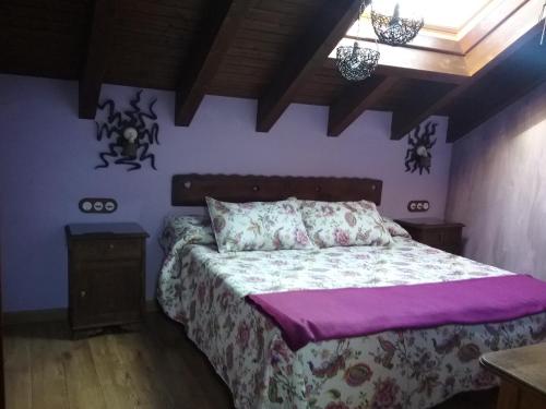 a bedroom with a bed with a purple blanket at El Conventu del Asturcon in Lago