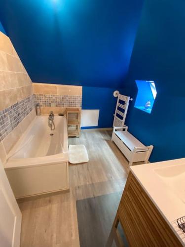 La salle de bains est pourvue d'une baignoire blanche et d'un mur bleu. dans l'établissement Grande et belle maison ancienne restaurée, à Écrainville