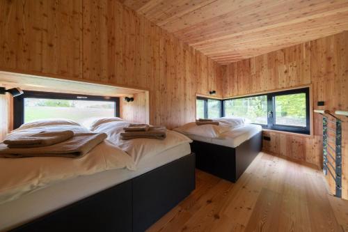 two beds in a room with wooden walls at Treeangle - K1 Baumhaus in Odenthal