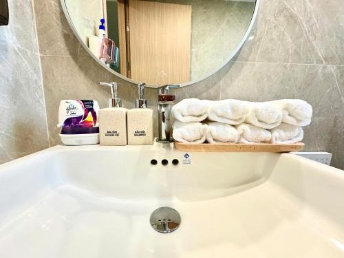 a bathroom with a bath tub with a mirror and towels at Saigon Luxury Apartment in Long Bình
