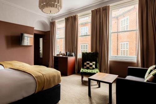 a hotel room with a bed and a chair and windows at The Brewers Inn in London