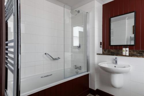 a bathroom with a tub and a sink and a mirror at The Brewers Inn in London