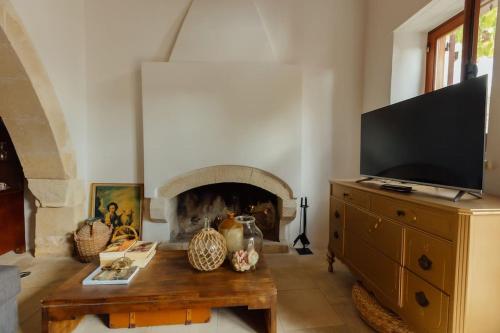 a living room with a tv and a fireplace at The Yard Traditional Residence in Vasa Kilaniou