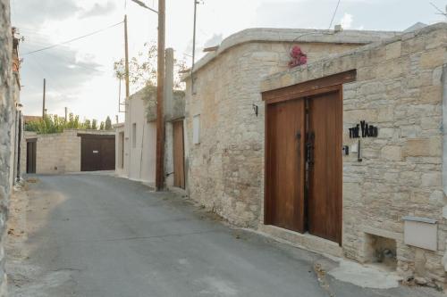 an alley with a stone building with a wooden door at The Yard Traditional Residence in Vasa Kilaniou