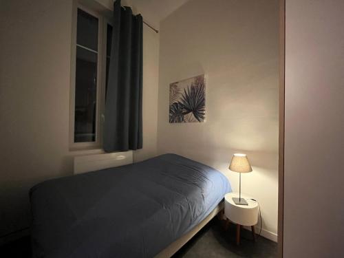 une chambre avec un lit, une lampe et une fenêtre dans l'établissement La Cathédrale, à Reims