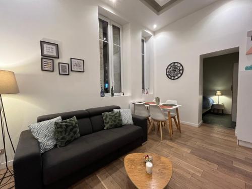 un salon avec un canapé noir et une table dans l'établissement La Cathédrale, à Reims