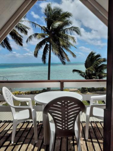 a table and chairs on a balcony with a view of the ocean at Maupiti Authentique in Te-Fare-Arii