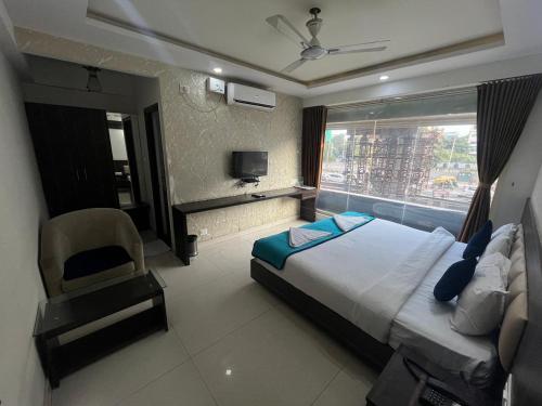 a bedroom with a bed and a chair and a window at Western Keys Hotel in Bengaluru