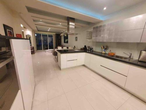 a kitchen with white cabinets and a large white floor at Charming 2-bedroom 2 bath apartment - Sliema in Sliema