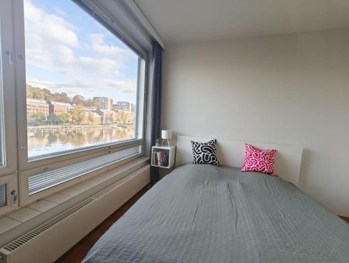 a bedroom with a large window and a bed with pink pillows at Föri condo, sauna and parking in Turku