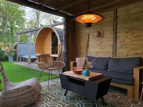 a living room with a couch and chairs on a patio at "ZeeLandZon" Holiday home by the lake with Jacuzzi and Sauna in Herkingen