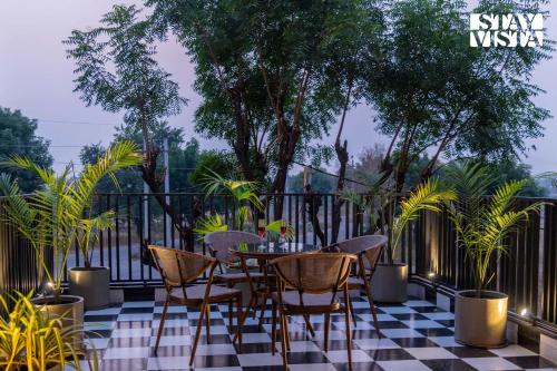a table and chairs on a balcony with trees at StayVista at Urban Escape - 2 Pools, Lawn & WiFi in Jaipur
