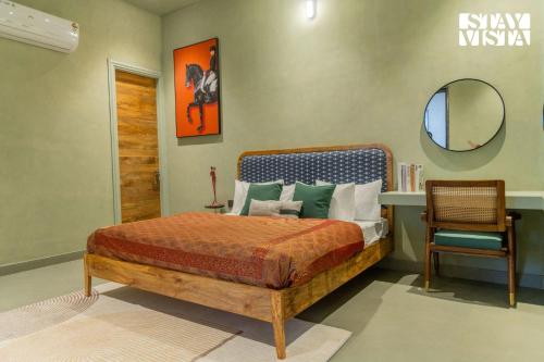 a bedroom with a bed and a mirror and a chair at StayVista at Urban Escape - 2 Pools, Lawn & WiFi in Jaipur