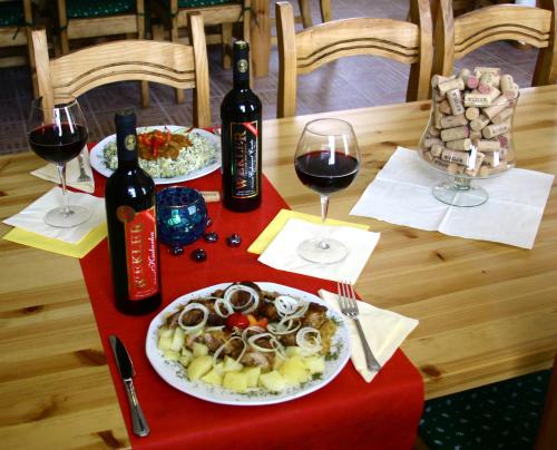 a table with two plates of food and two glasses of wine at Wekler Családi Pincészet és Panzió in Mecseknádasd
