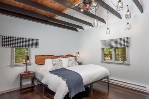 a bedroom with a bed with white walls and windows at The Biddle House by AvantStay Breathtaking Views Walk to Lake in Lake Harmony