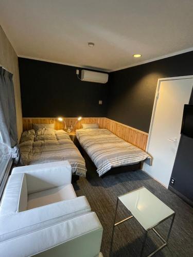 a room with two beds and a couch and a table at Restmance Pension Woody Hill in Iiyama