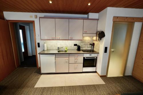a kitchen with white cabinets and a sink at Chalet Schwendiboden in Grindelwald