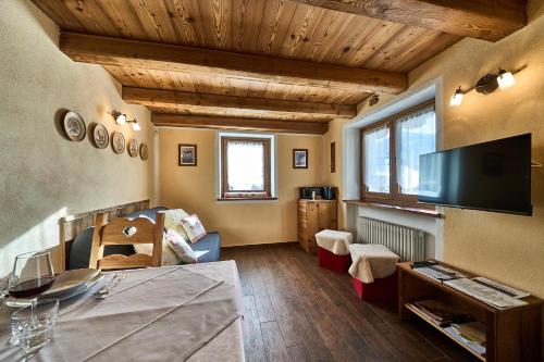 a living room with wooden ceilings and a television at MCX Vacation Rental - MAISON LOZ duplex in typical village in Valtournenche with modern comforts just 2 minutes from the cable cars! in Valtournenche