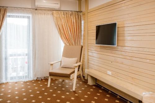 a room with a chair and a flat screen tv at Chevalier Hotel & SPA in Bukovel