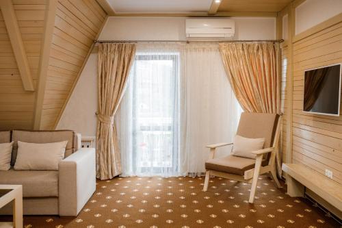 a living room with a couch and a chair and a window at Chevalier Hotel & SPA in Bukovel