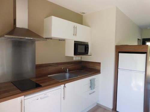 a kitchen with white cabinets and a sink and a microwave at Village de Gîtes Nature et Jardin in Bouère