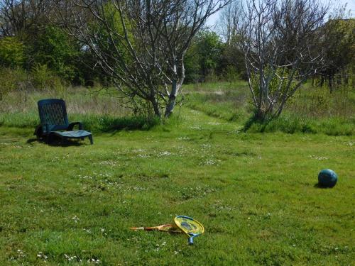 a kite in the grass next to a chair and a ball at Village de Gîtes Nature et Jardin in Bouère