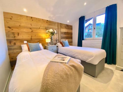 two beds in a hotel room with blue curtains at Les Trois Pointes in Morzine